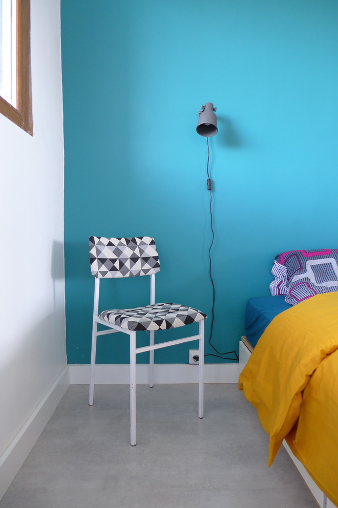Cette image montre une chambre parentale design de taille moyenne avec un mur bleu, sol en béton ciré, aucune cheminée et un sol gris.