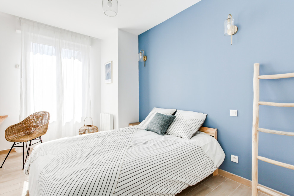 Idées déco pour une grande chambre parentale bord de mer avec un mur bleu, tomettes au sol et un sol beige.