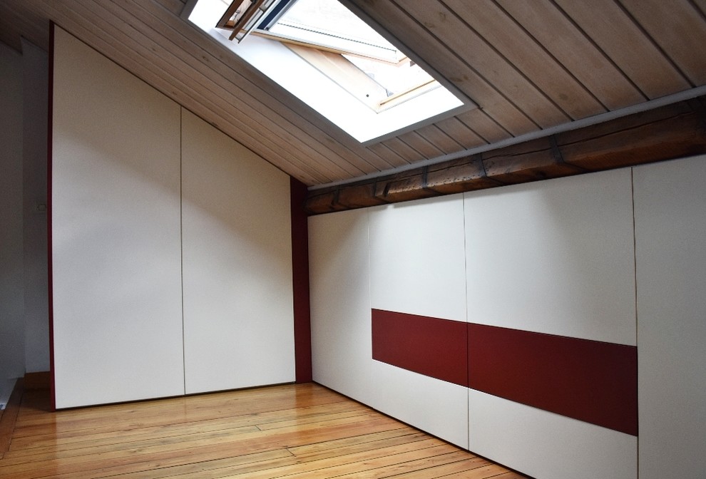 Modelo de dormitorio tipo loft contemporáneo grande sin chimenea con suelo de madera clara
