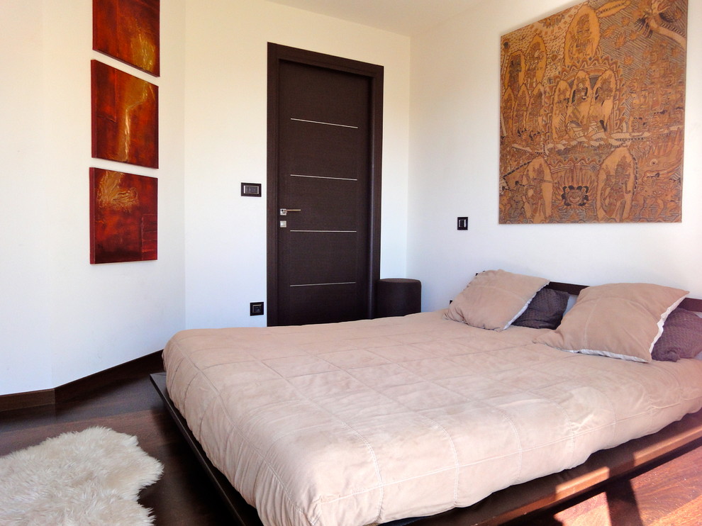 Exemple d'une chambre parentale tendance de taille moyenne avec un mur blanc, parquet foncé, aucune cheminée et un sol marron.