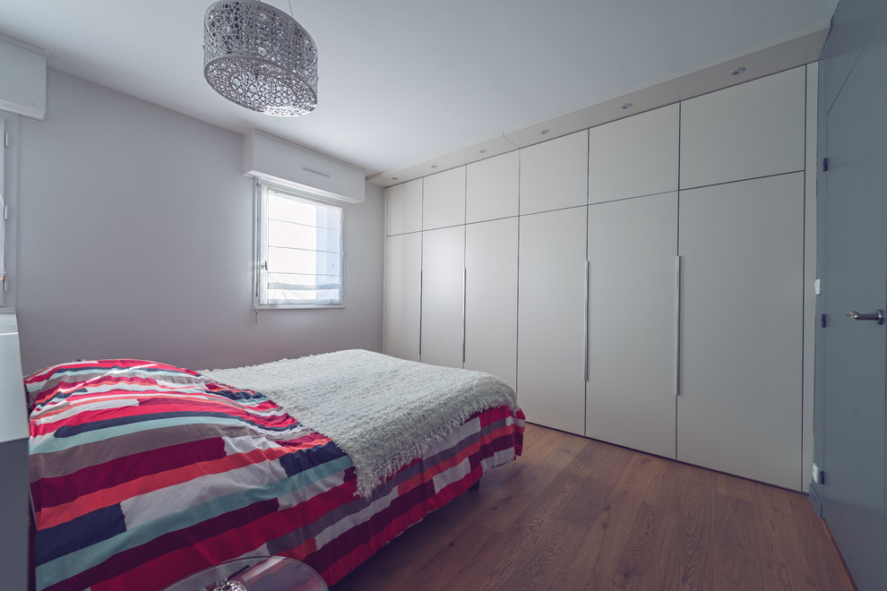 На фото: большая хозяйская спальня в современном стиле с серыми стенами и паркетным полом среднего тона с