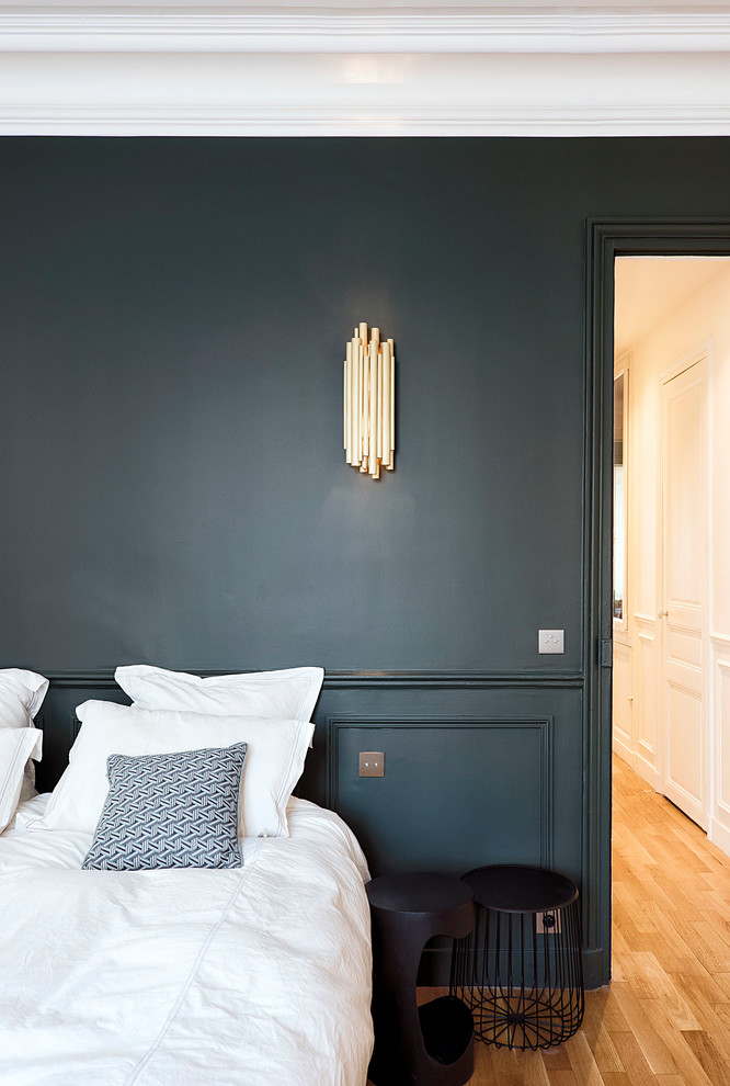 Cette image montre une chambre parentale design de taille moyenne avec une cheminée standard, un manteau de cheminée en pierre, un mur bleu, parquet foncé et un sol marron.