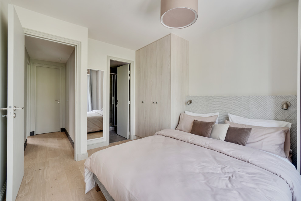 Inspiration pour une chambre d'amis design avec un mur blanc, un sol en bois clair et un sol beige.