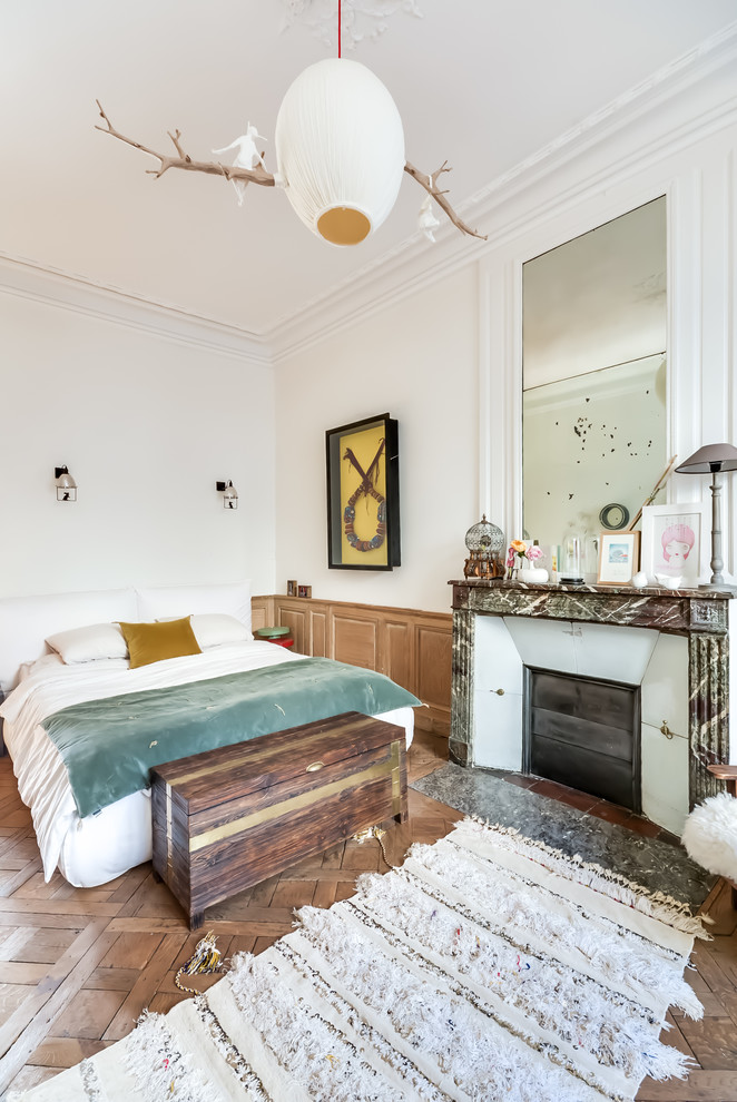 Großes Eklektisches Hauptschlafzimmer mit weißer Wandfarbe, braunem Holzboden, Kamin und Kaminumrandung aus Stein in Paris