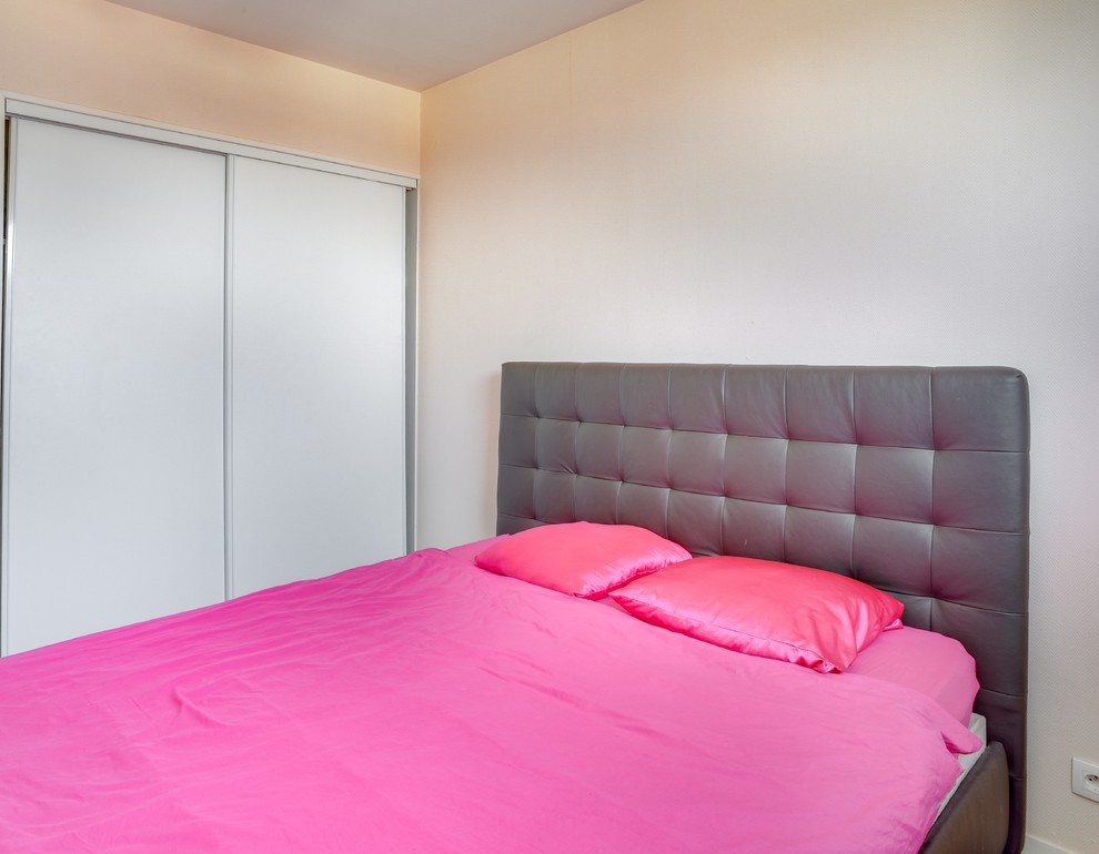 Cette image montre une petite chambre bohème avec un mur rose, aucune cheminée et un sol gris.