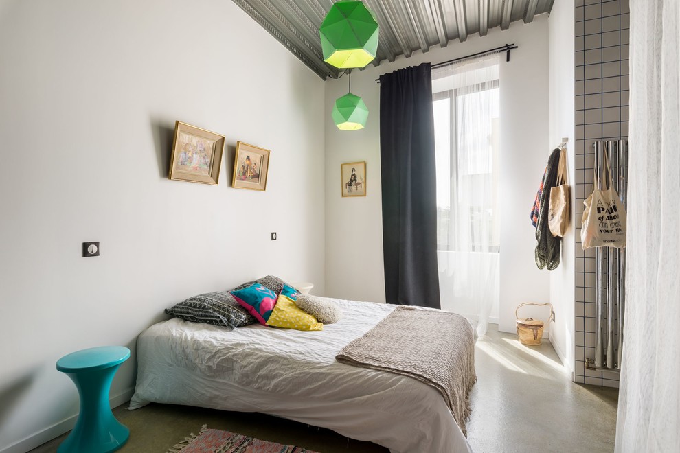 Imagen de dormitorio principal ecléctico de tamaño medio sin chimenea con paredes blancas y suelo de cemento