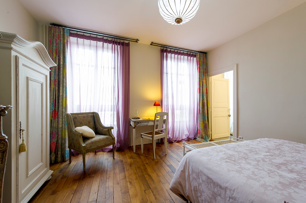 Imagen de dormitorio principal clásico renovado con paredes beige y suelo de madera en tonos medios