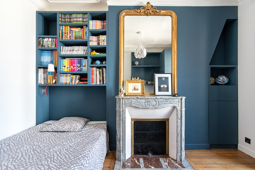 Idéer för ett klassiskt sovrum, med blå väggar, mellanmörkt trägolv, en standard öppen spis, en spiselkrans i sten och brunt golv