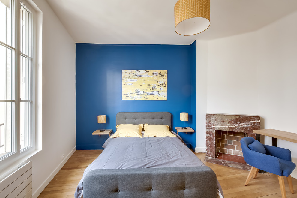 Cette image montre une chambre design avec un mur blanc, une cheminée standard et un sol marron.