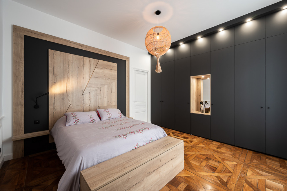 Idée de décoration pour une chambre design de taille moyenne avec un mur blanc et un sol marron.