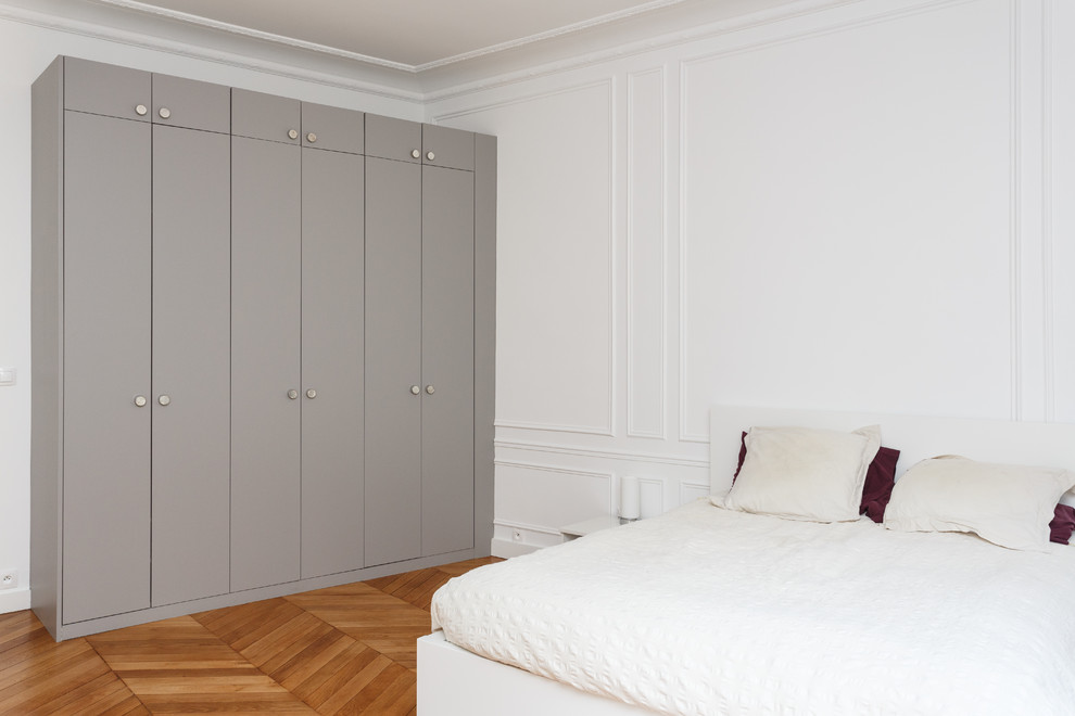 Imagen de dormitorio principal nórdico grande sin chimenea con paredes blancas, suelo de madera en tonos medios y suelo marrón