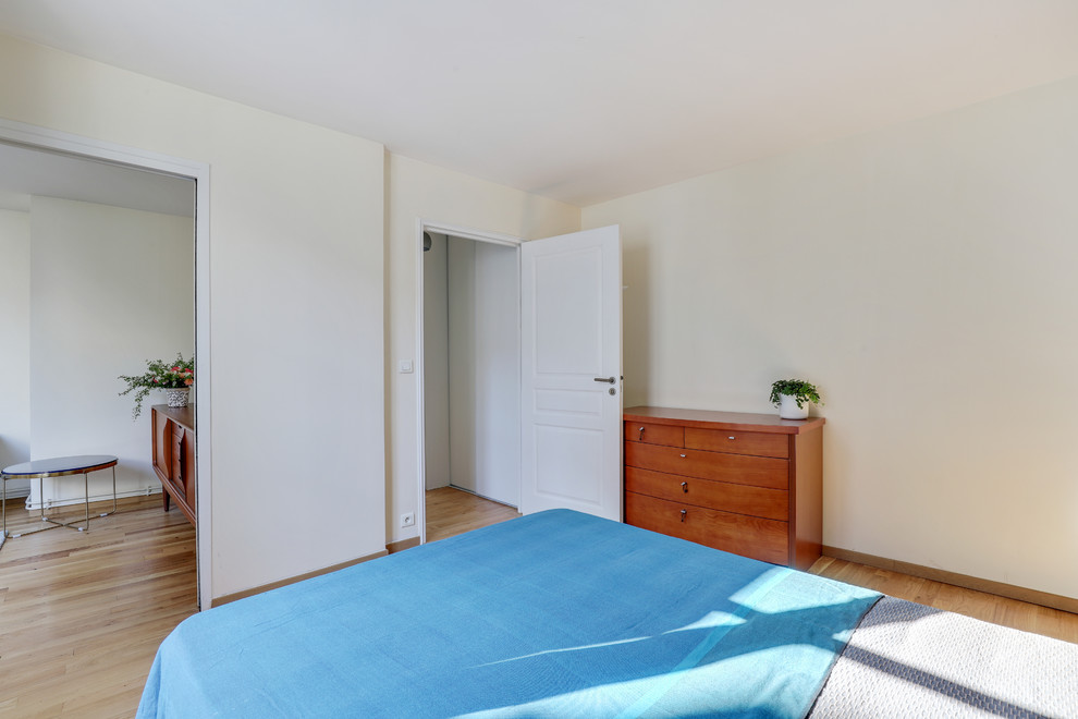 Exemple d'une grande chambre tendance avec un mur beige, parquet clair et un sol marron.