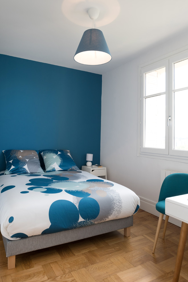 Cette image montre une chambre parentale nordique de taille moyenne avec un mur bleu, parquet clair et aucune cheminée.