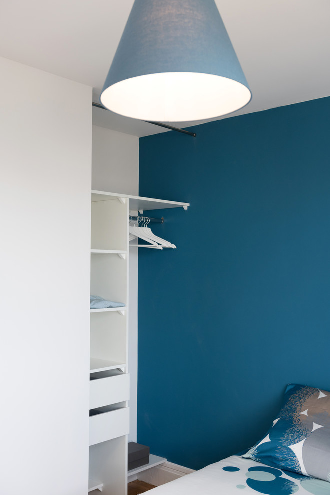 Ejemplo de dormitorio principal escandinavo de tamaño medio sin chimenea con paredes azules y suelo de madera clara