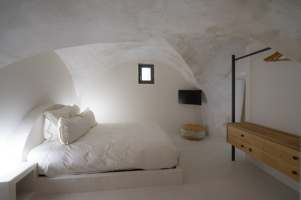 Esempio di una camera matrimoniale mediterranea di medie dimensioni con pavimento in cemento e pavimento bianco