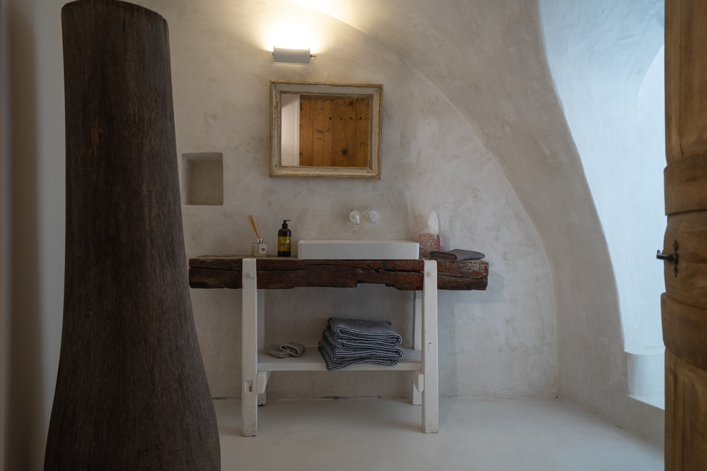他の地域にある中くらいな地中海スタイルのおしゃれな主寝室 (コンクリートの床、白い床)