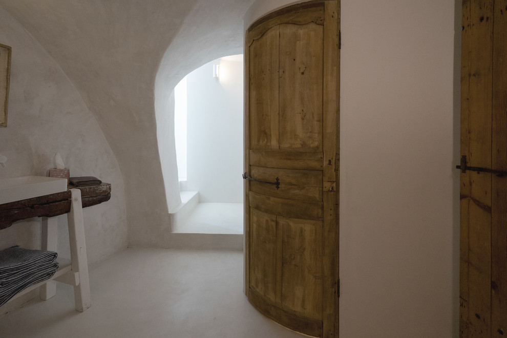 Imagen de dormitorio principal mediterráneo de tamaño medio con paredes blancas, suelo de cemento y suelo blanco