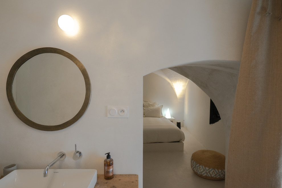 Modelo de dormitorio principal mediterráneo de tamaño medio con suelo de cemento y suelo blanco