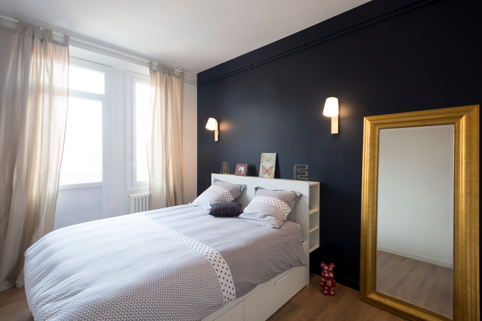 Ejemplo de dormitorio principal nórdico grande sin chimenea con paredes azules y suelo de madera clara
