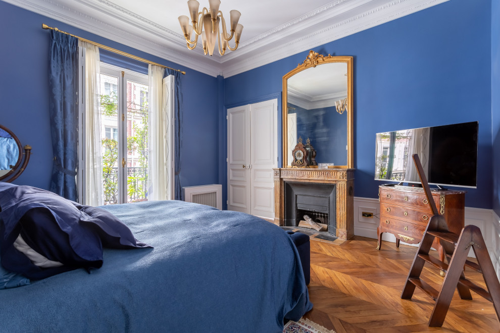 На фото: большая хозяйская спальня в стиле неоклассика (современная классика) с синими стенами, паркетным полом среднего тона, стандартным камином и коричневым полом с