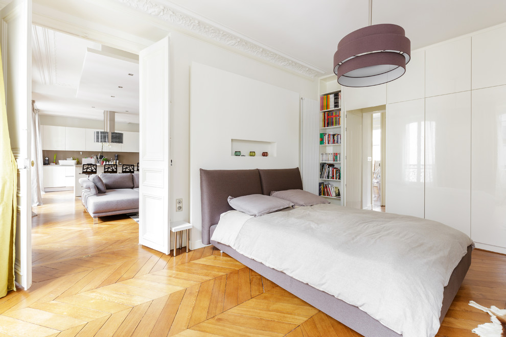 Aménagement d'une grande chambre parentale blanche et bois et haussmannienne contemporaine avec un mur blanc et un sol en bois brun.