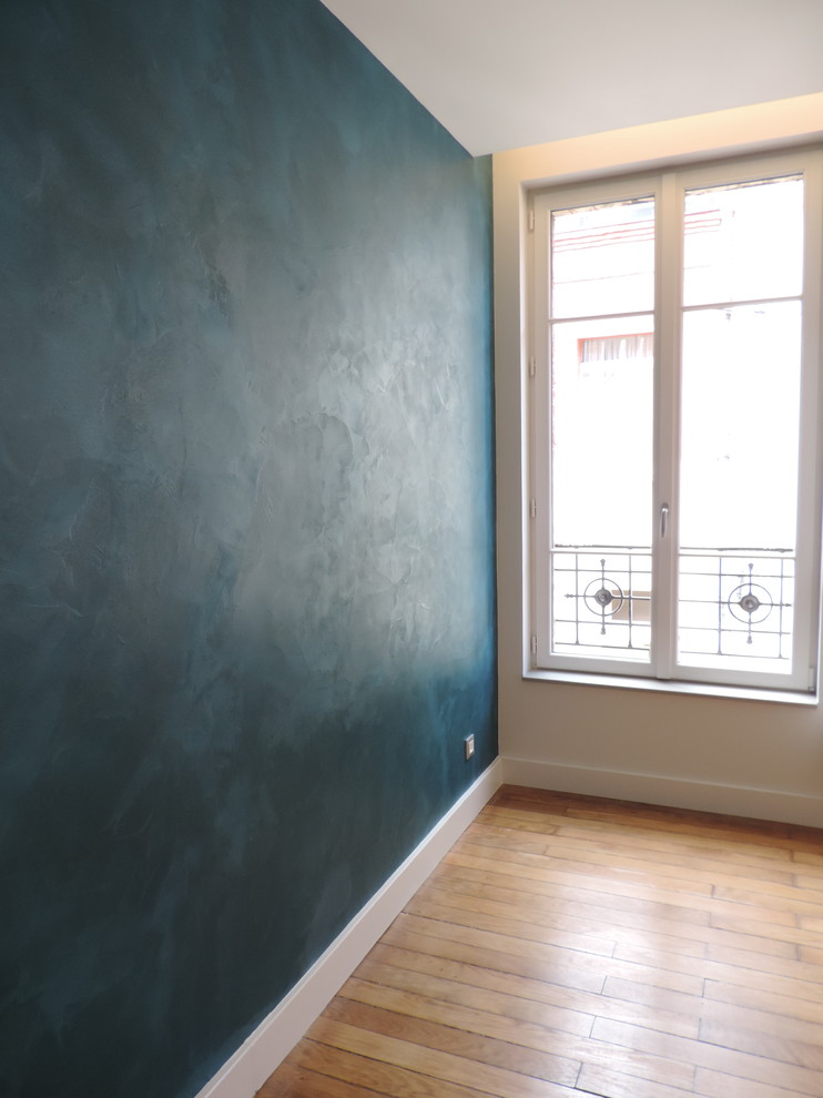 Aménagement d'une chambre d'amis moderne de taille moyenne avec un mur bleu et parquet clair.