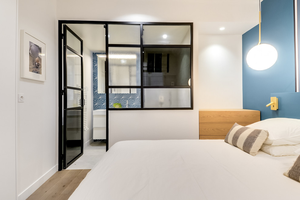 Modelo de dormitorio principal actual de tamaño medio sin chimenea con paredes azules, suelo de madera oscura y suelo marrón