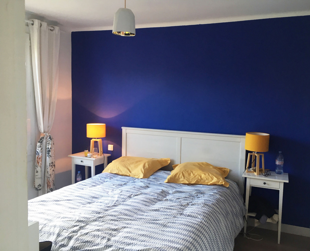Cette image montre une chambre méditerranéenne avec un mur bleu et sol en stratifié.