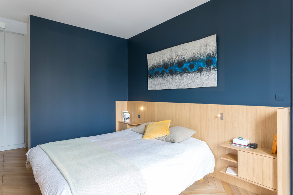 Cette image montre une chambre design avec un mur bleu, parquet clair et un sol beige.