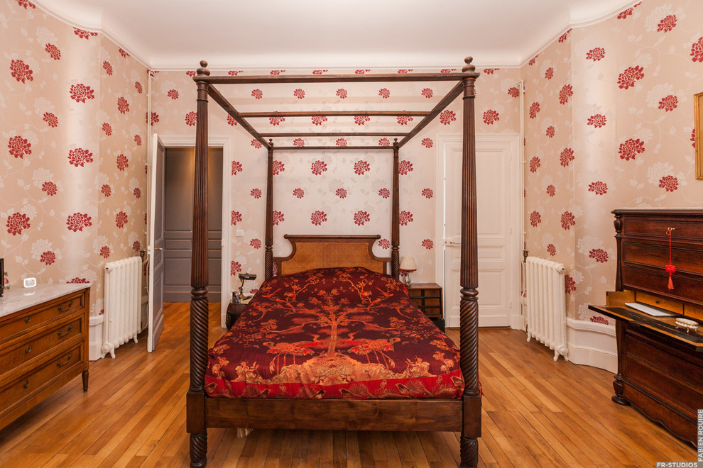 Пример оригинального дизайна: хозяйская спальня среднего размера в викторианском стиле с красными стенами, светлым паркетным полом, стандартным камином и фасадом камина из камня