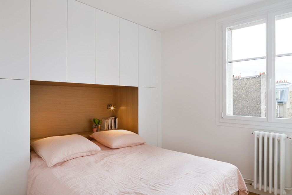 This is an example of a small contemporary master bedroom in Paris with white walls and light hardwood flooring.