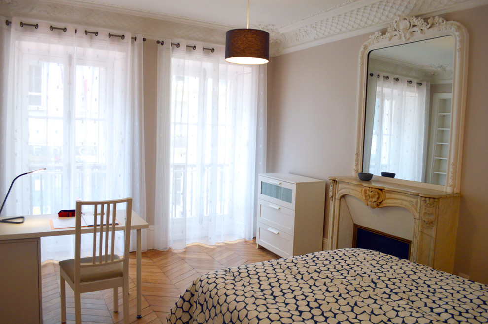 Imagen de dormitorio principal clásico de tamaño medio con paredes grises, suelo de madera clara, todas las chimeneas y marco de chimenea de yeso