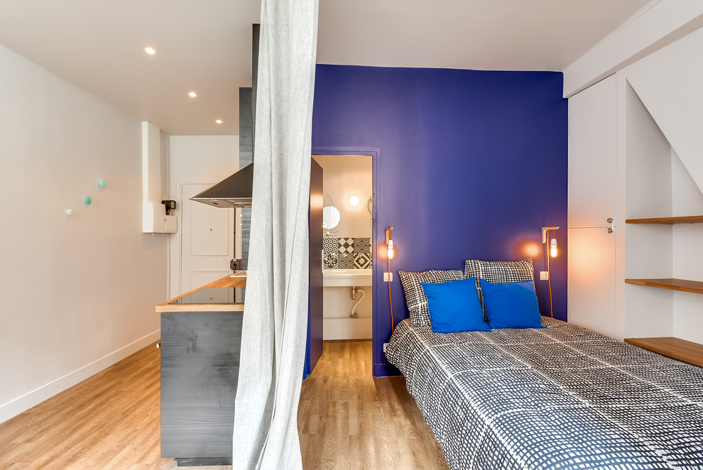 Imagen de dormitorio principal actual de tamaño medio con paredes azules y suelo de madera clara