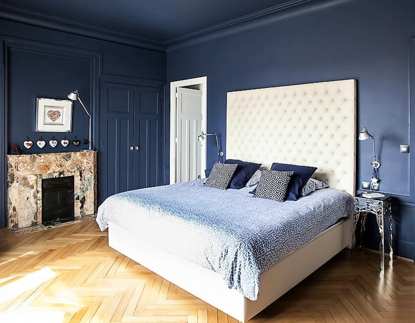 Photo of a medium sized classic master bedroom in Lyon with blue walls, light hardwood flooring, a standard fireplace, a stone fireplace surround and beige floors.