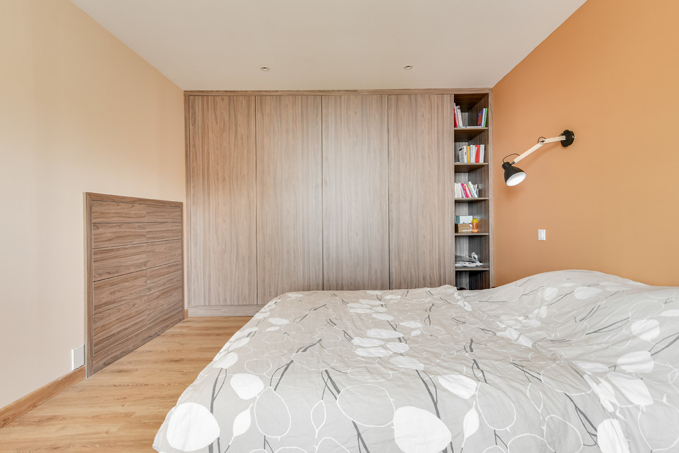 Imagen de dormitorio principal de estilo de casa de campo de tamaño medio sin chimenea con parades naranjas y suelo de madera clara