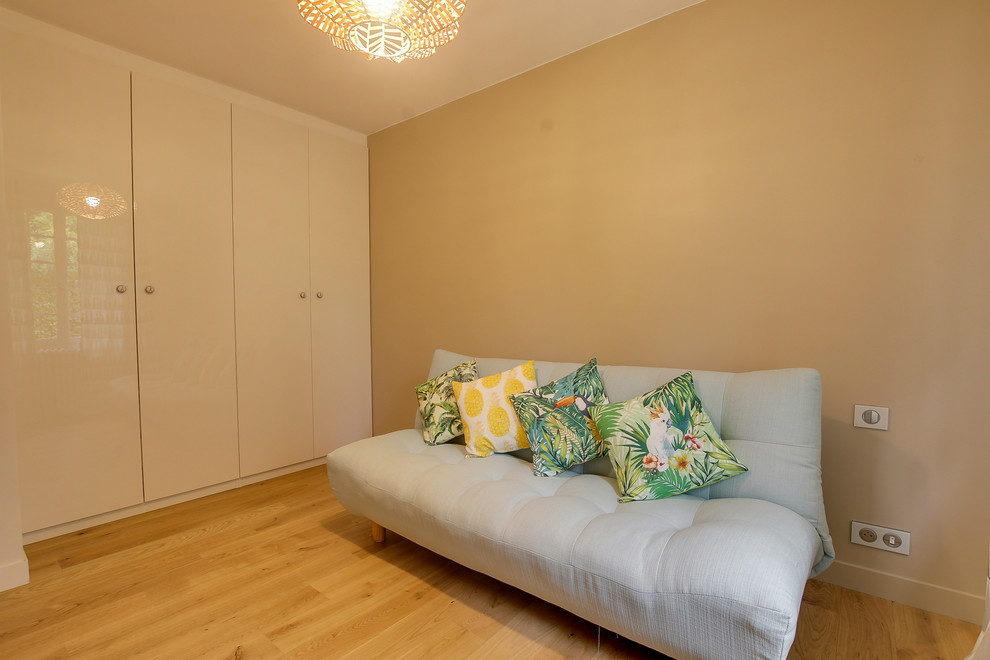 Exemple d'une chambre d'amis éclectique de taille moyenne avec un mur beige, parquet clair, aucune cheminée et un sol marron.
