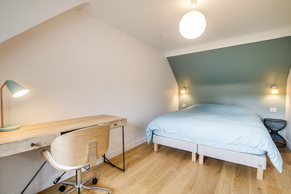Cette image montre une chambre d'amis bohème de taille moyenne avec un mur bleu, parquet clair, aucune cheminée et un sol marron.