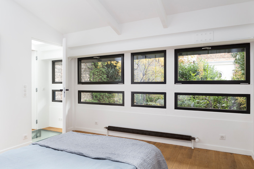 Idées déco pour une chambre parentale contemporaine de taille moyenne avec un mur bleu, un sol en bois brun et un sol beige.