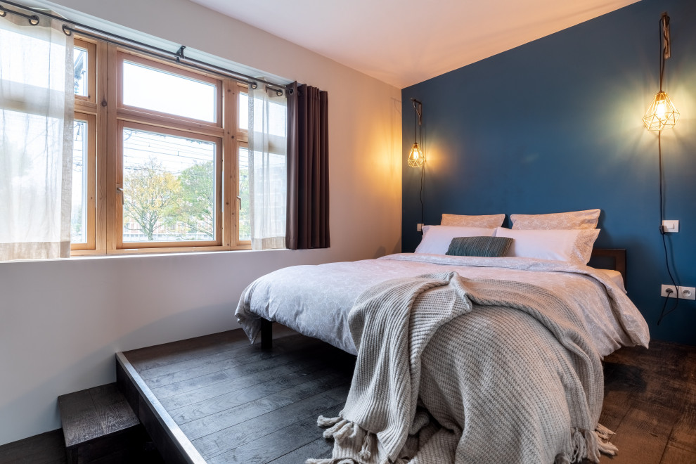 Exemple d'une chambre parentale tendance de taille moyenne avec un mur bleu, parquet foncé, aucune cheminée et un sol marron.