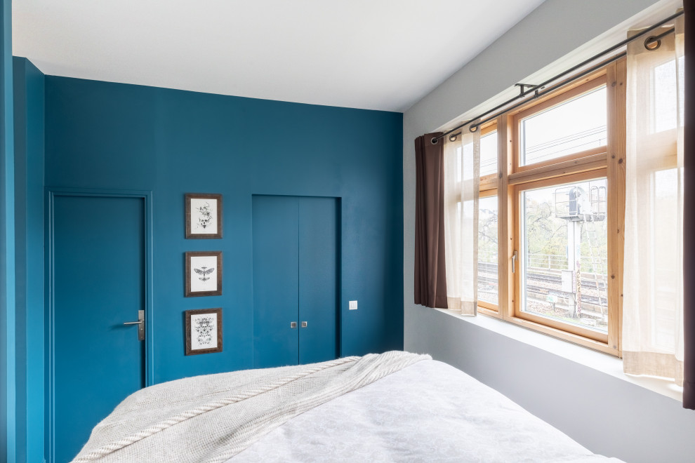 This is an example of a medium sized contemporary master bedroom in Paris with blue walls, dark hardwood flooring, no fireplace and brown floors.