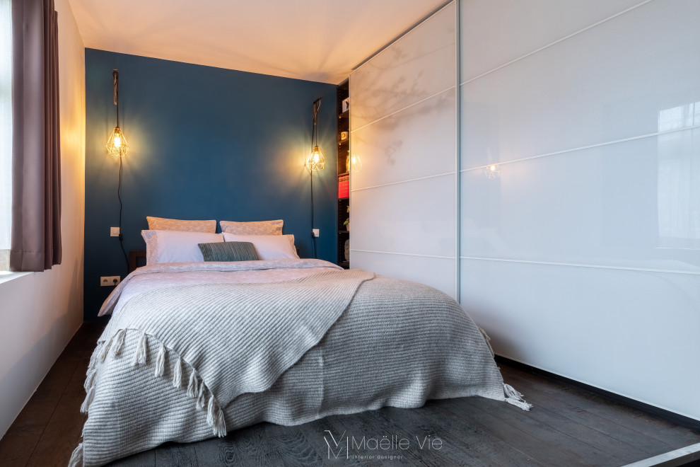 Idée de décoration pour une chambre parentale design de taille moyenne avec un mur bleu, parquet foncé, aucune cheminée et un sol marron.