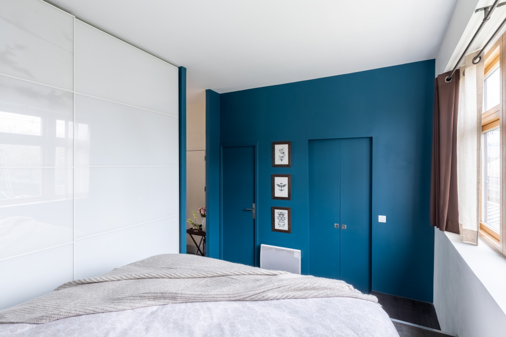 Idées déco pour une chambre parentale contemporaine de taille moyenne avec un mur bleu, parquet foncé, aucune cheminée et un sol marron.