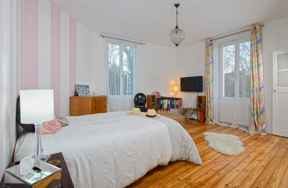 Cette image montre une chambre parentale design de taille moyenne avec un mur blanc, un sol en bois brun, aucune cheminée et un sol marron.