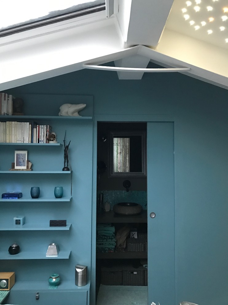 Eklektisk inredning av ett sovrum, med blå väggar och mellanmörkt trägolv