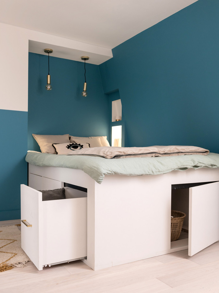 Small trendy light wood floor and beige floor bedroom photo in Other with blue walls