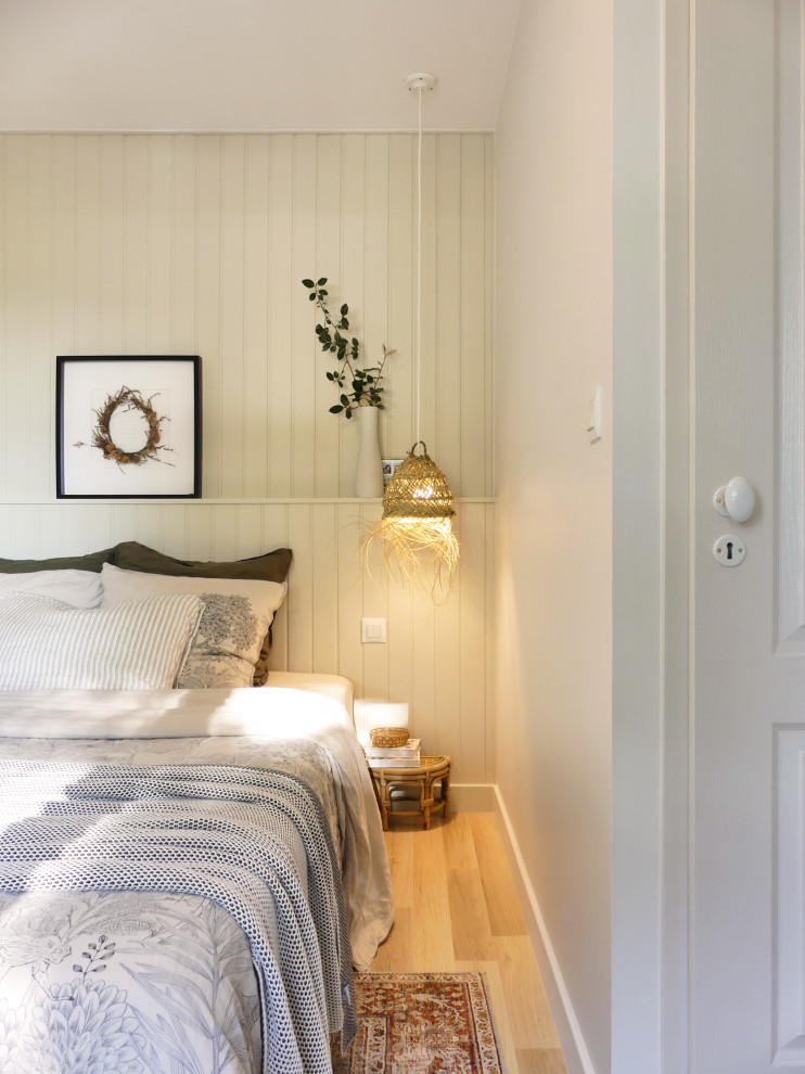 Ejemplo de dormitorio principal marinero de tamaño medio con paredes beige, suelo de madera clara, suelo marrón y panelado