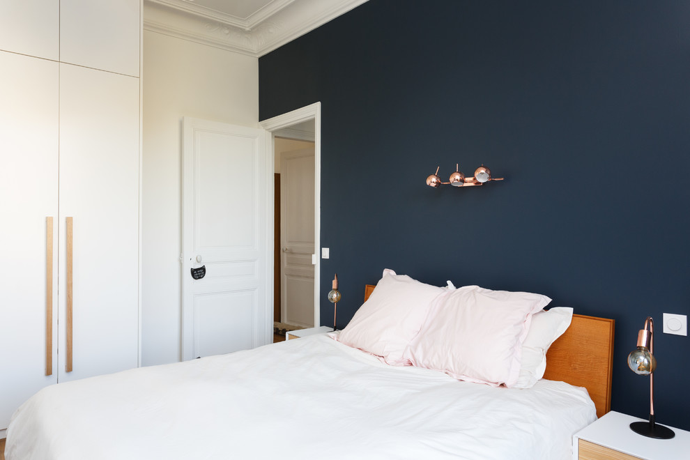 Réalisation d'une chambre parentale nordique de taille moyenne avec un mur bleu, un sol en bois brun, une cheminée standard, un manteau de cheminée en pierre et un sol marron.