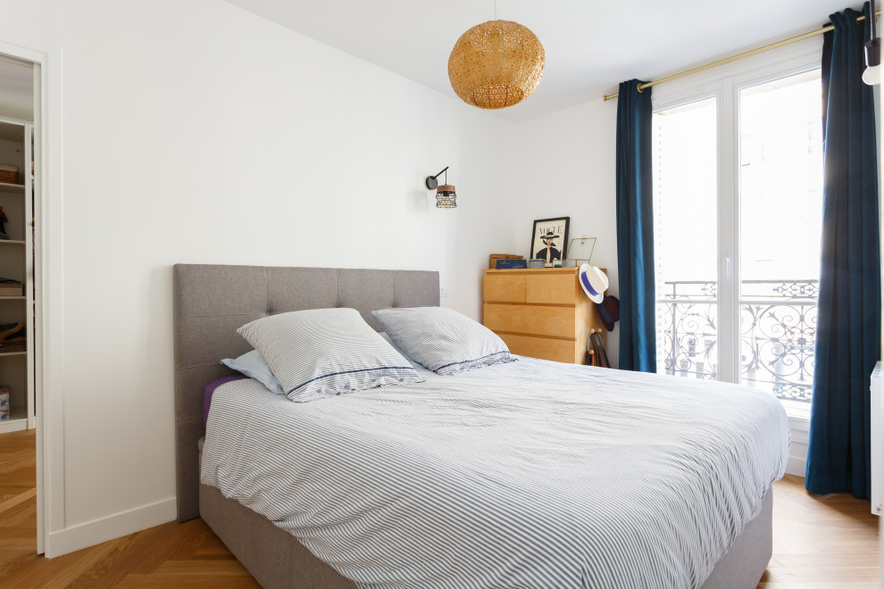 Modelo de dormitorio principal nórdico de tamaño medio sin chimenea con paredes blancas, suelo de madera clara y suelo beige
