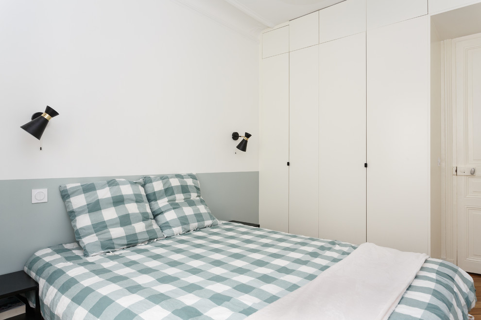 Mittelgroßes Modernes Hauptschlafzimmer ohne Kamin mit weißer Wandfarbe, braunem Holzboden und braunem Boden in Paris