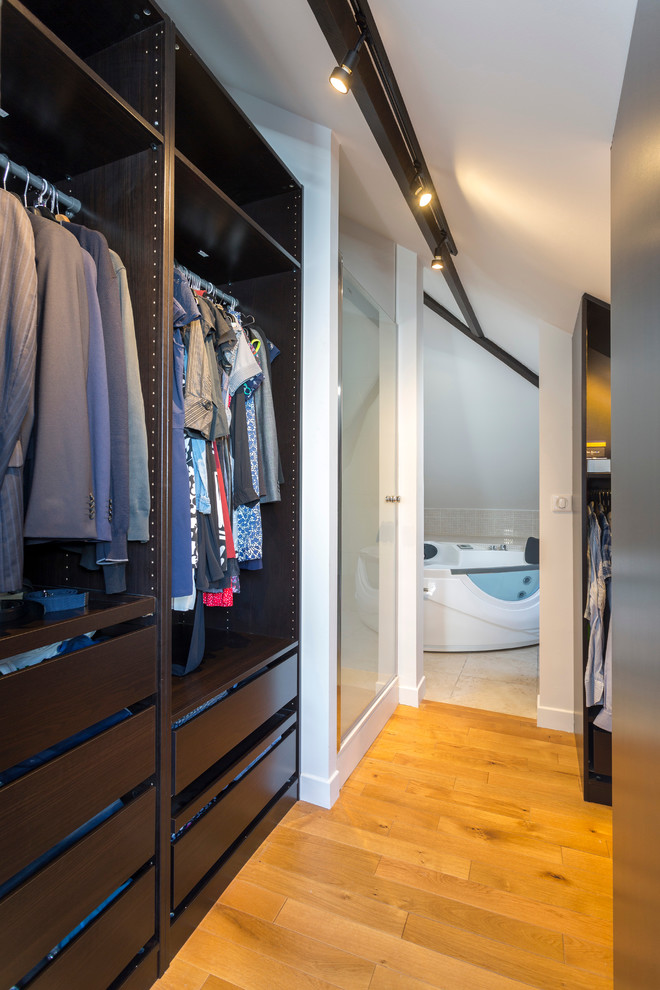 Foto de armario y vestidor actual grande con suelo de madera clara y suelo beige